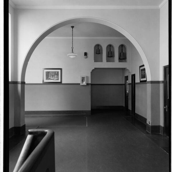 Interior shot of the school showing a hallway with decorative bells set on the wall.