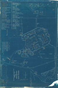 Blueprint showing a large farm and the location of dozens of buildings in relation to the center farm area. Roads, trees, ponds, and other pathways are shown. A legend connects building numbers with the names of buildings. Circa 1906.